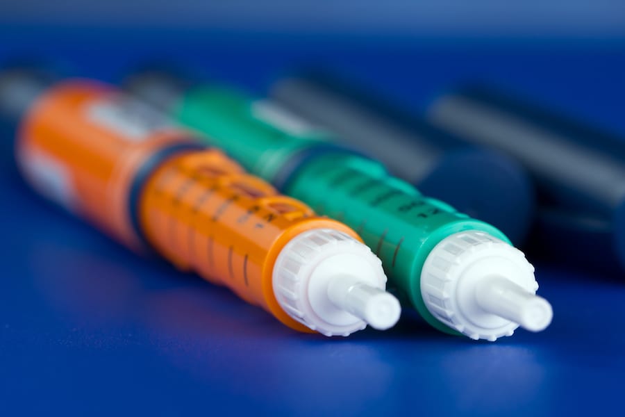 Close up of green and orange insulin syringe pens